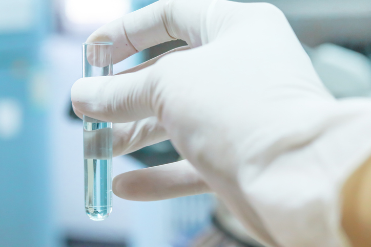 A gloved hand holding a test tube filled with water